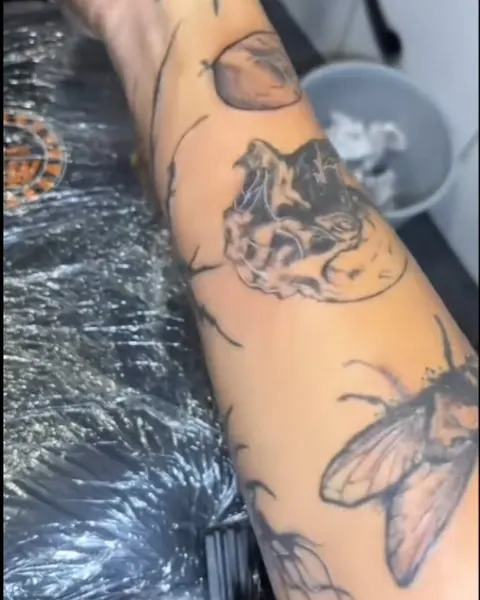 Patchwork forearm tattoos including a moth and a skull