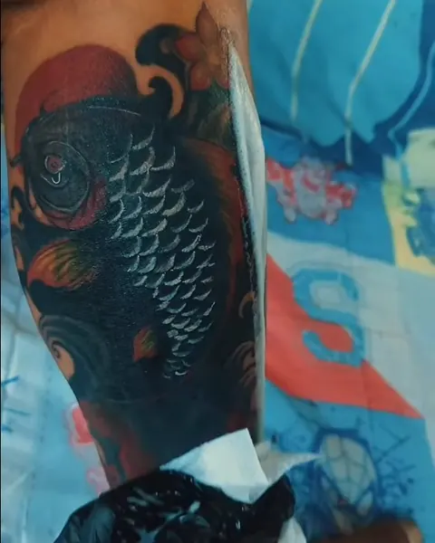Color koi fish tattoo on an upper arm in Japanese style